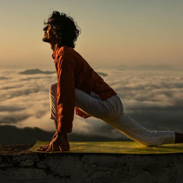 Silhouette of a man stretching against a sunrise, symbolizing well-being.